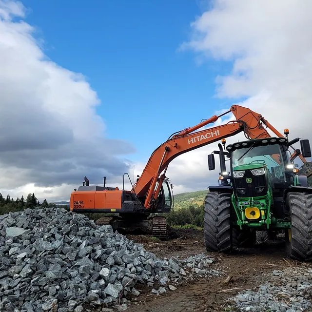 Gravemaskin legger stein over i lasteplan