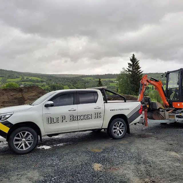 Firmabil med liten gravemaskin på tilhenger