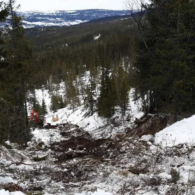 Graving av vei i snødekt skog