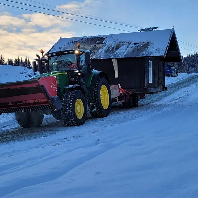 Traktor med lite hus på lasteplan