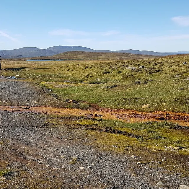 Gravemaskin på grusvei i fjellområde