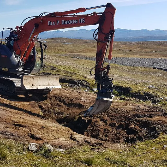 Gravemaskin i arbeid i fjellområde